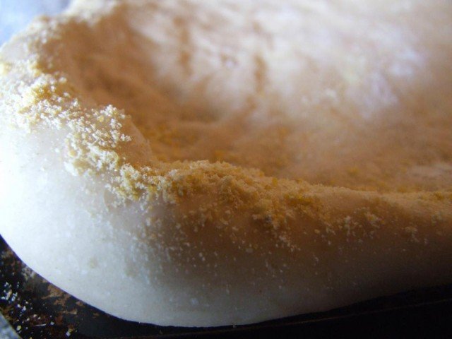 Cornmeal sprinkled around the edge of the pizza dough