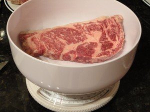 Hand Cut Rib Eye Steaks Being Weighed Individually on a Kitchen Scale